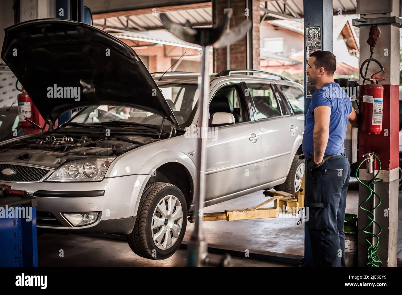 Car mechanic working in a repair garage with hydraulic car lift. Automobile elevator Stock Photo