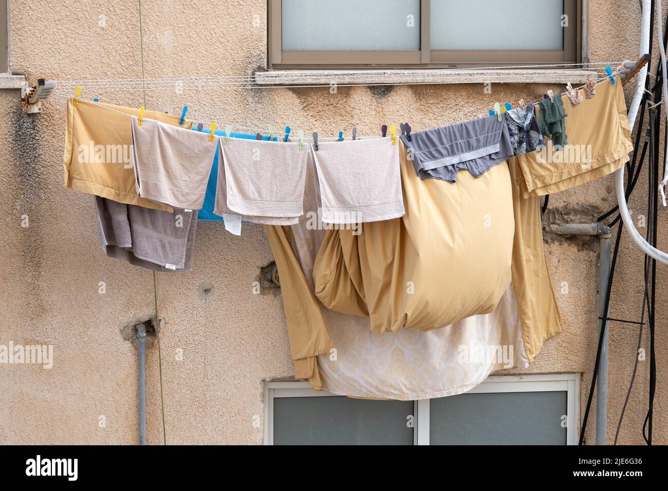Bed linen and clothes are dried on a rope in the street in Israel Stock Photo