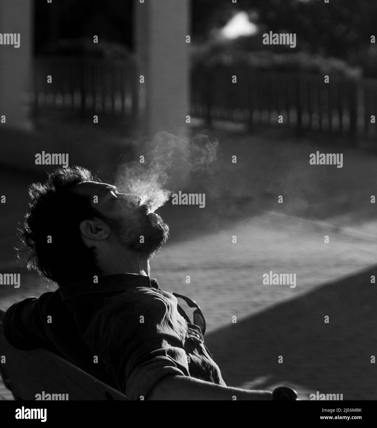 thoughtful man smoking a cigarette alone in black and white selective focus Stock Photo