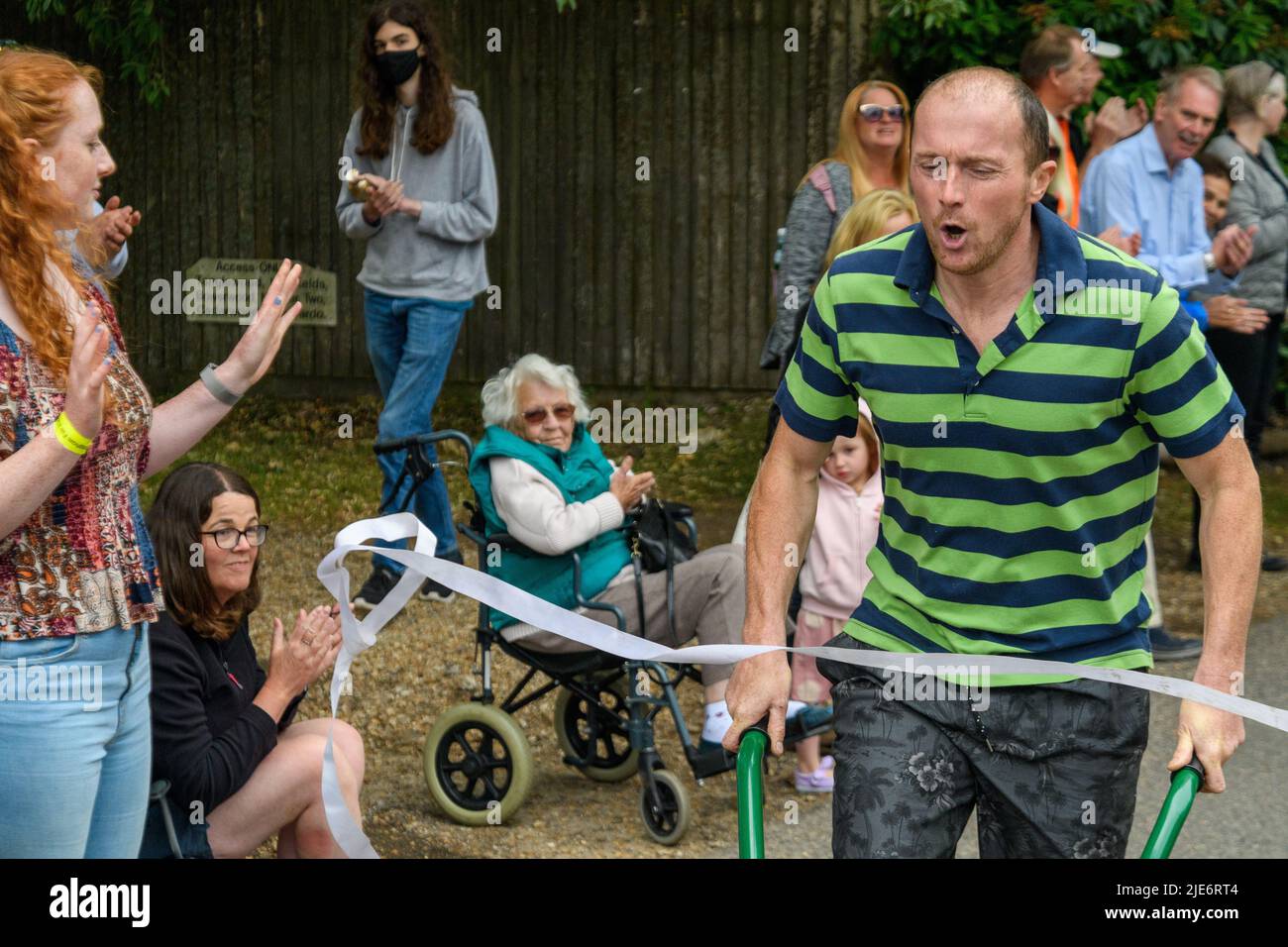 New Forest, Hampshire, UK, 25th June 2022: A competitor feels the pain at the finish line in the wheelbarrow race at Frogham Fair, Frogham, Fordingbridge. The physically demanding timed races take place up Blissford Hill which has a 1 in 4 incline. Credit: Paul Biggins/Alamy Live News Stock Photo