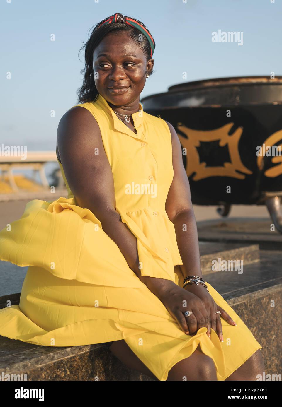 African woman sitting with yellow dress at sunset in Independence Arch