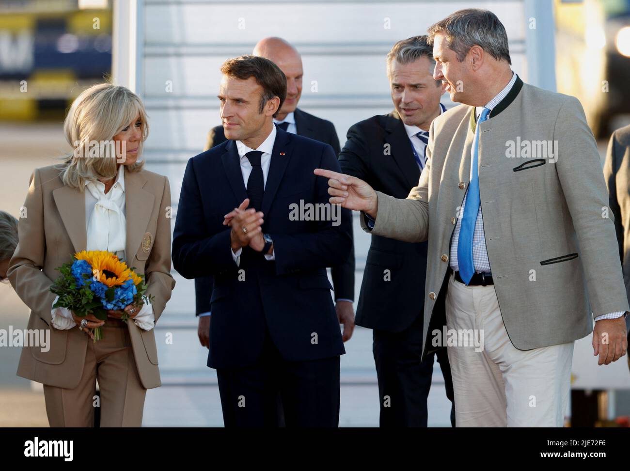 French President Emmanuel Macron's wife Brigitte Macron holds flowers given by children in traditional Bavarian clothes as she speaks with Bavaria's State Premier Markus Soeder upon arrival at Franz-Josef-Strauss airport in Munich ahead of the G7 summit, which will take place in the Bavarian alpine resort of Elmau Castle, Germany, June 25, 2022. REUTERS/Michaela Rehle Stock Photo