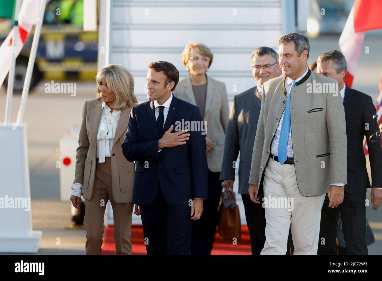 People in traditional Bavarian clothes and Bavaria's State Premier Markus Soeder welcome French President Emmanuel Macron and his wife Brigitte Macron as they arrive at Franz-Josef-Strauss airport in Munich ahead of the G7 summit, which will take place in the Bavarian alpine resort of Elmau Castle, Germany, June 25, 2022. REUTERS/Michaela Rehle Stock Photo
