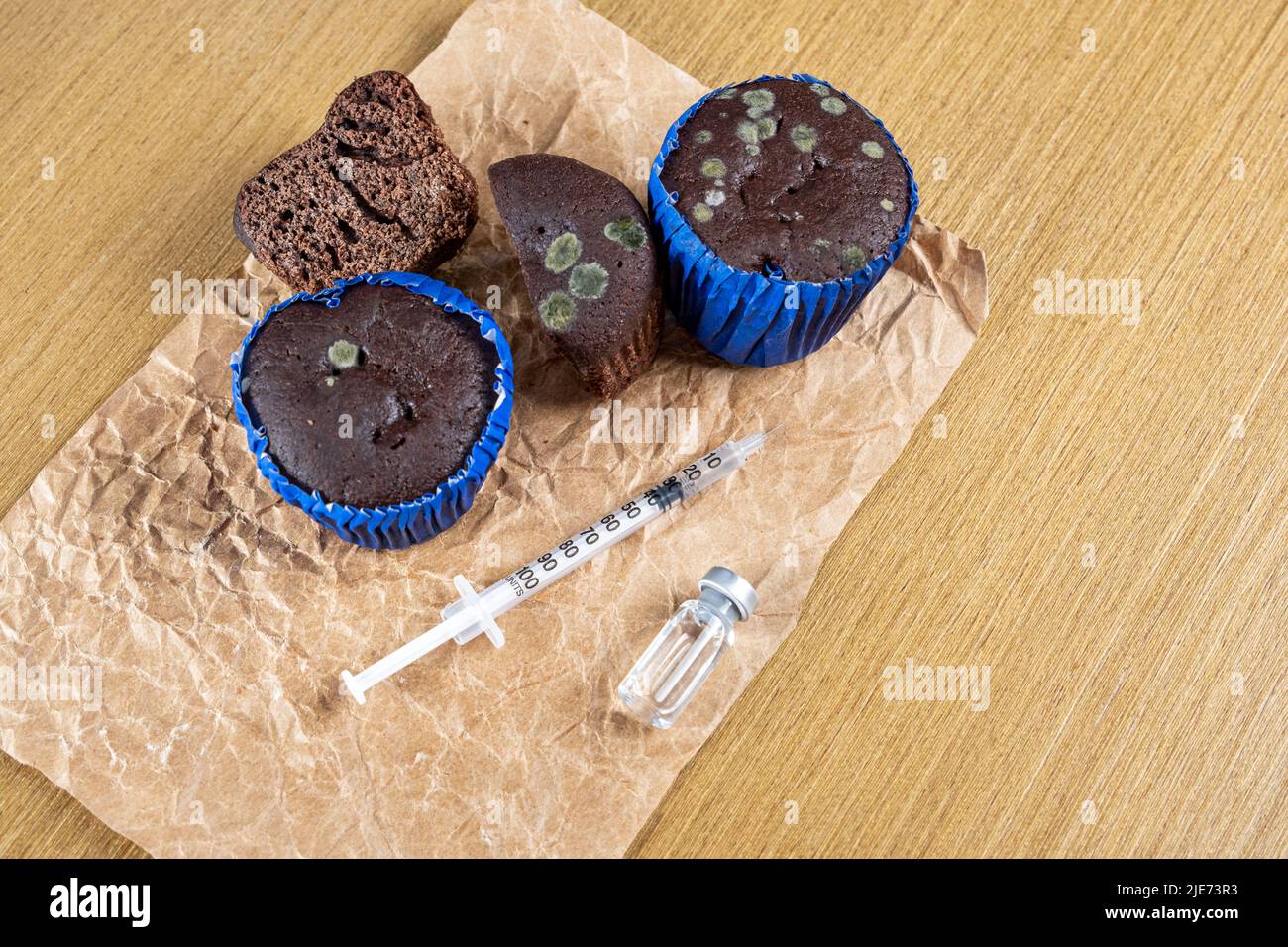 Syringe with insulin next to moldy muffins and ampoule. Stock Photo