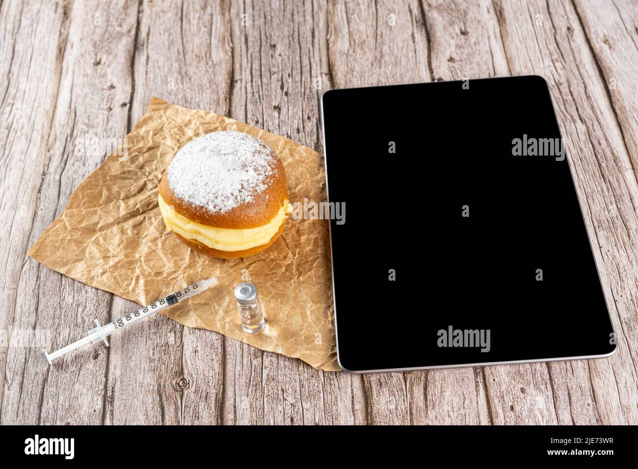 Brazilian cream doughnuts next to a syringe and an ampoule of insulin and a tablet. Stock Photo