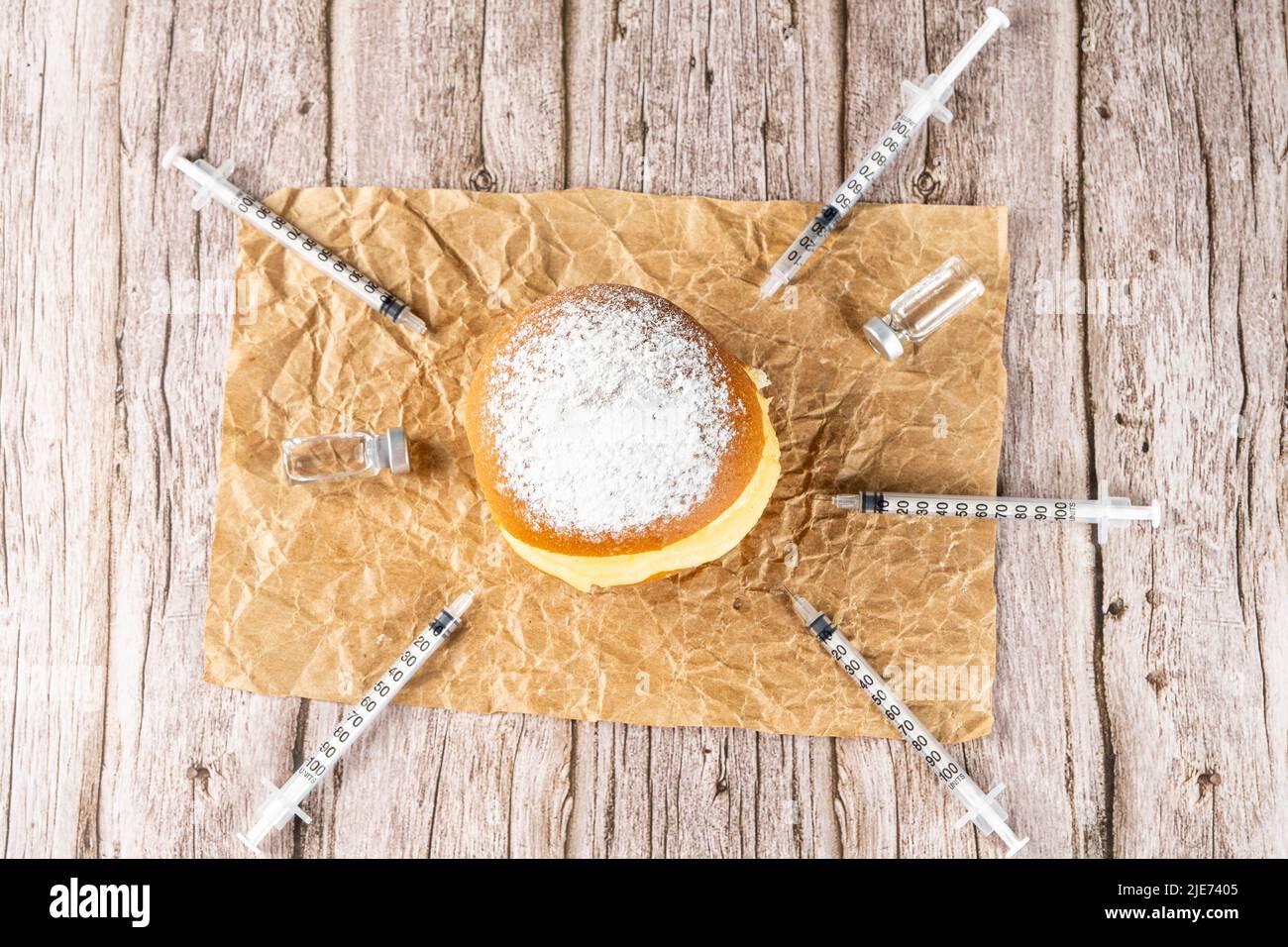 Brazilian cream doughnuts surrounded by various syringes and ampoules with insulin. Stock Photo