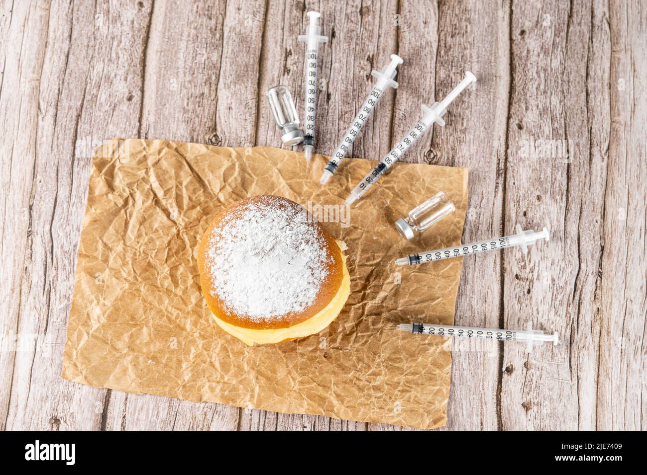 Brazilian cream doughnuts surrounded by various syringes and ampoules with insulin top view. Stock Photo