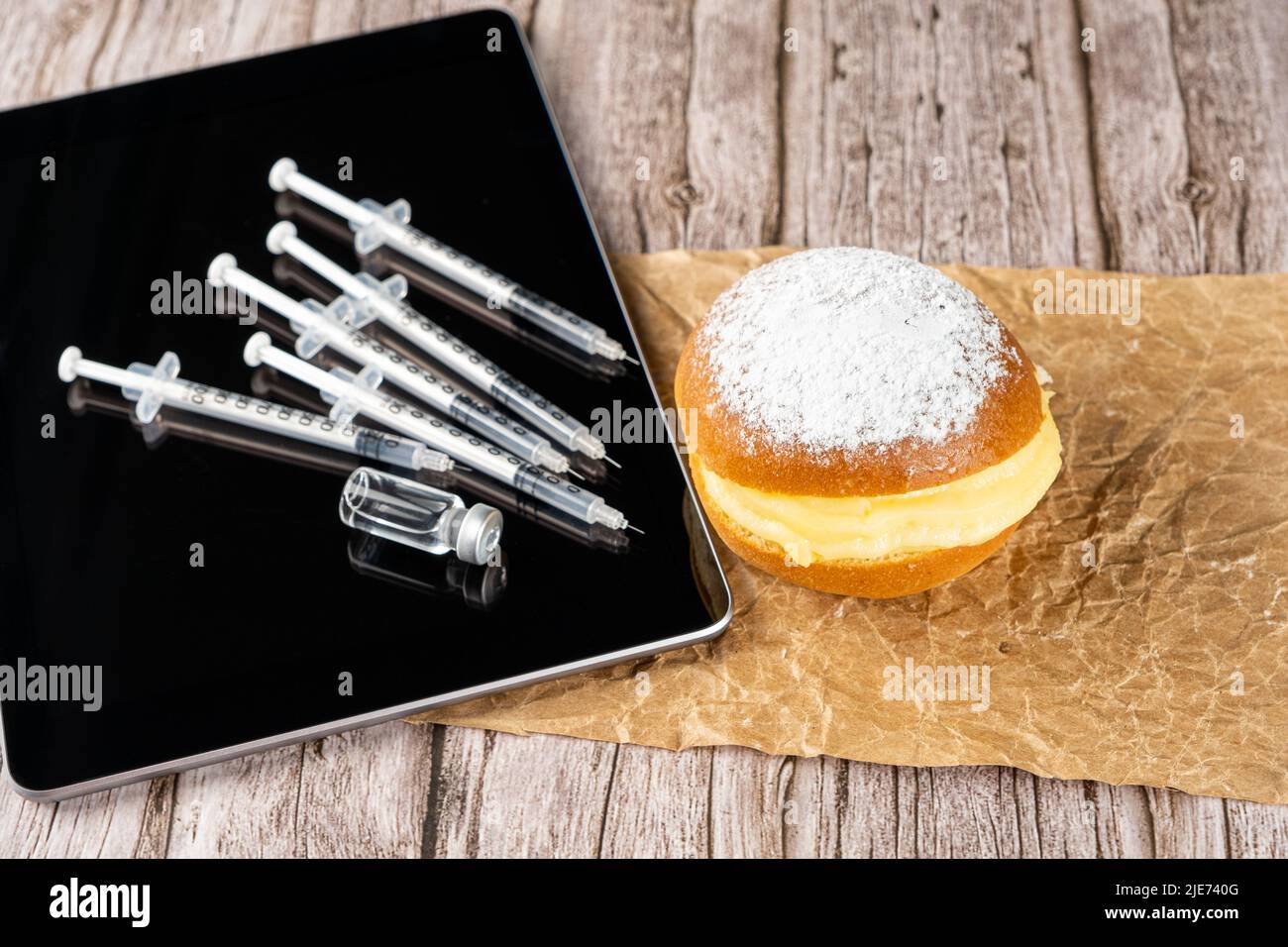 Brazilian cream doughnuts next by several syringes and ampoules with insulin on the tablet. Stock Photo
