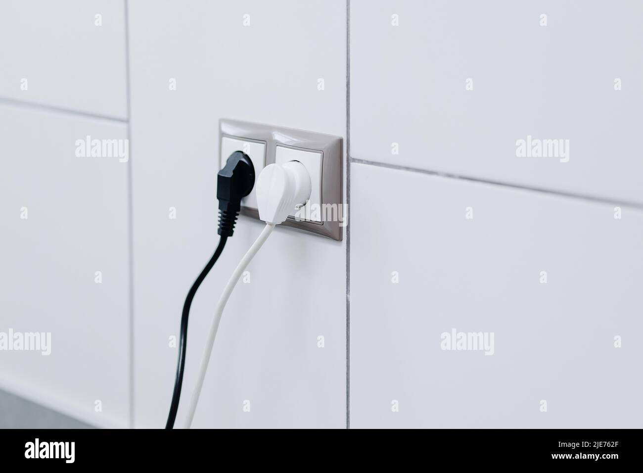 White and black cables in a socket on a white wall. High quality photo Stock Photo