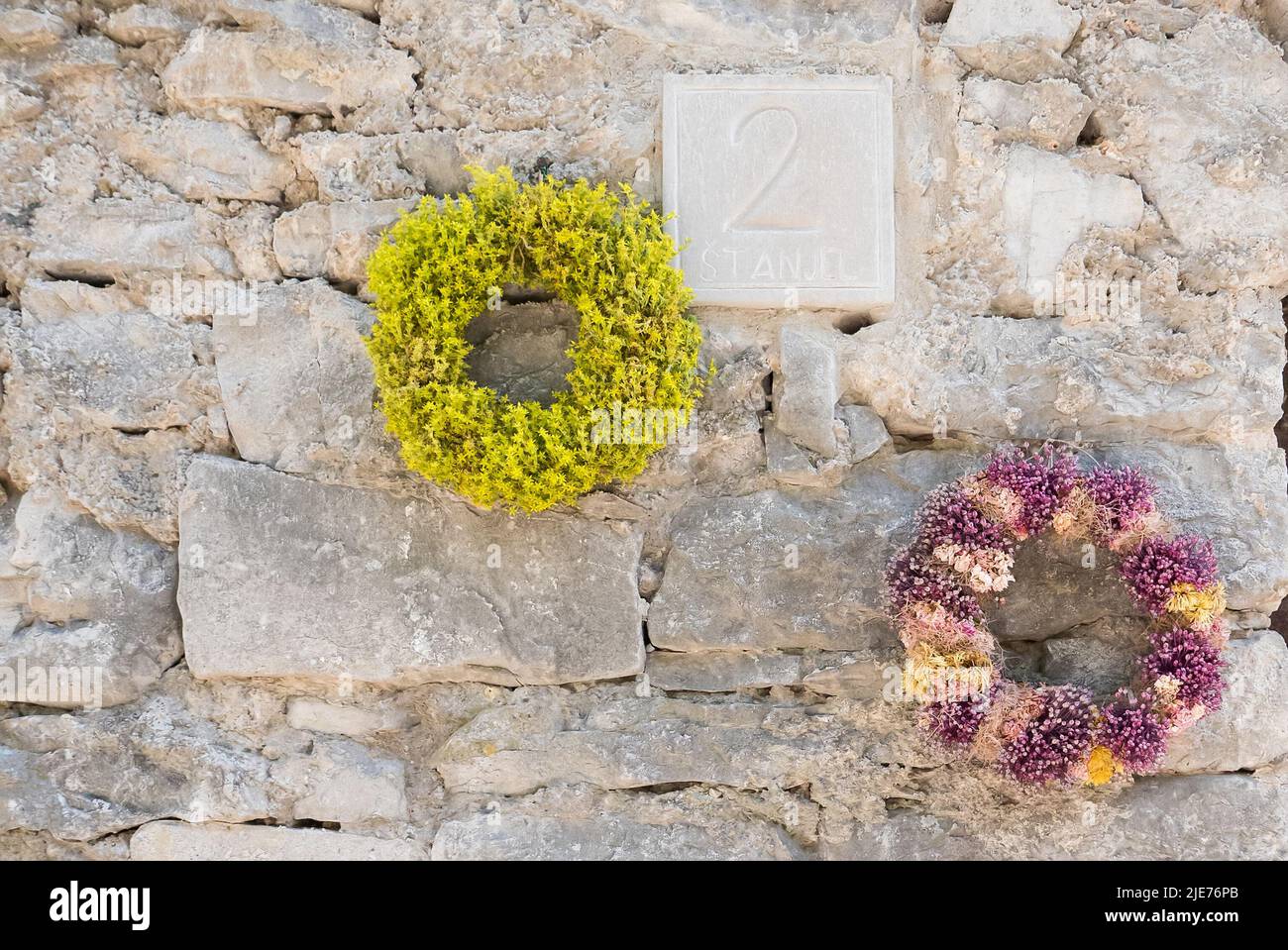 Two  wreath of flowers picked  up during the day of St. John and hanged near the entrance of an old house of Stanjel in Slovenia Stock Photo