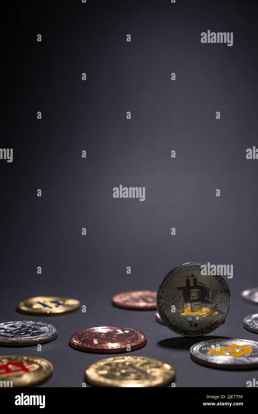 One Silver BTC Bitcoin close up, centered with other bitcoins coins lied on the desk on a dark background. Stock Photo