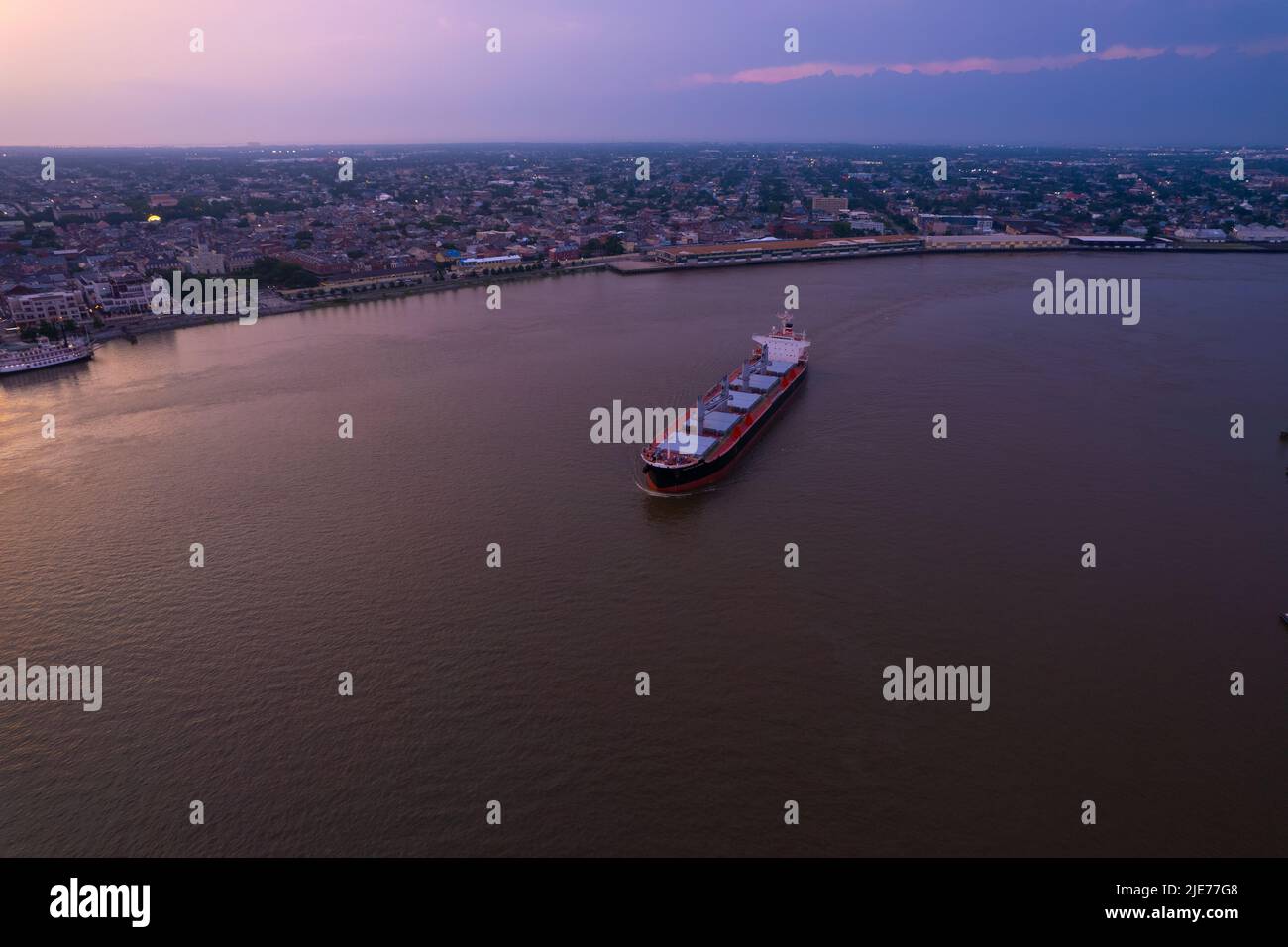 Ship turning on the river in New Orleans with a beautiful set set projecting over the city Stock Photo