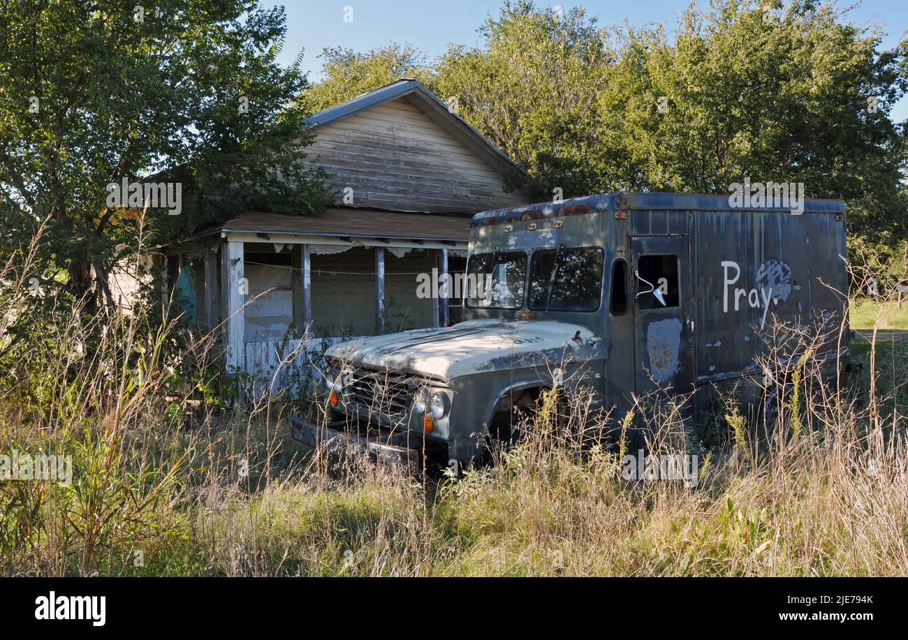 An old truck sits parked in front of an abandoned home on an overgrown property in the small Route 66 town of Texola, near the Texas state line. Stock Photo