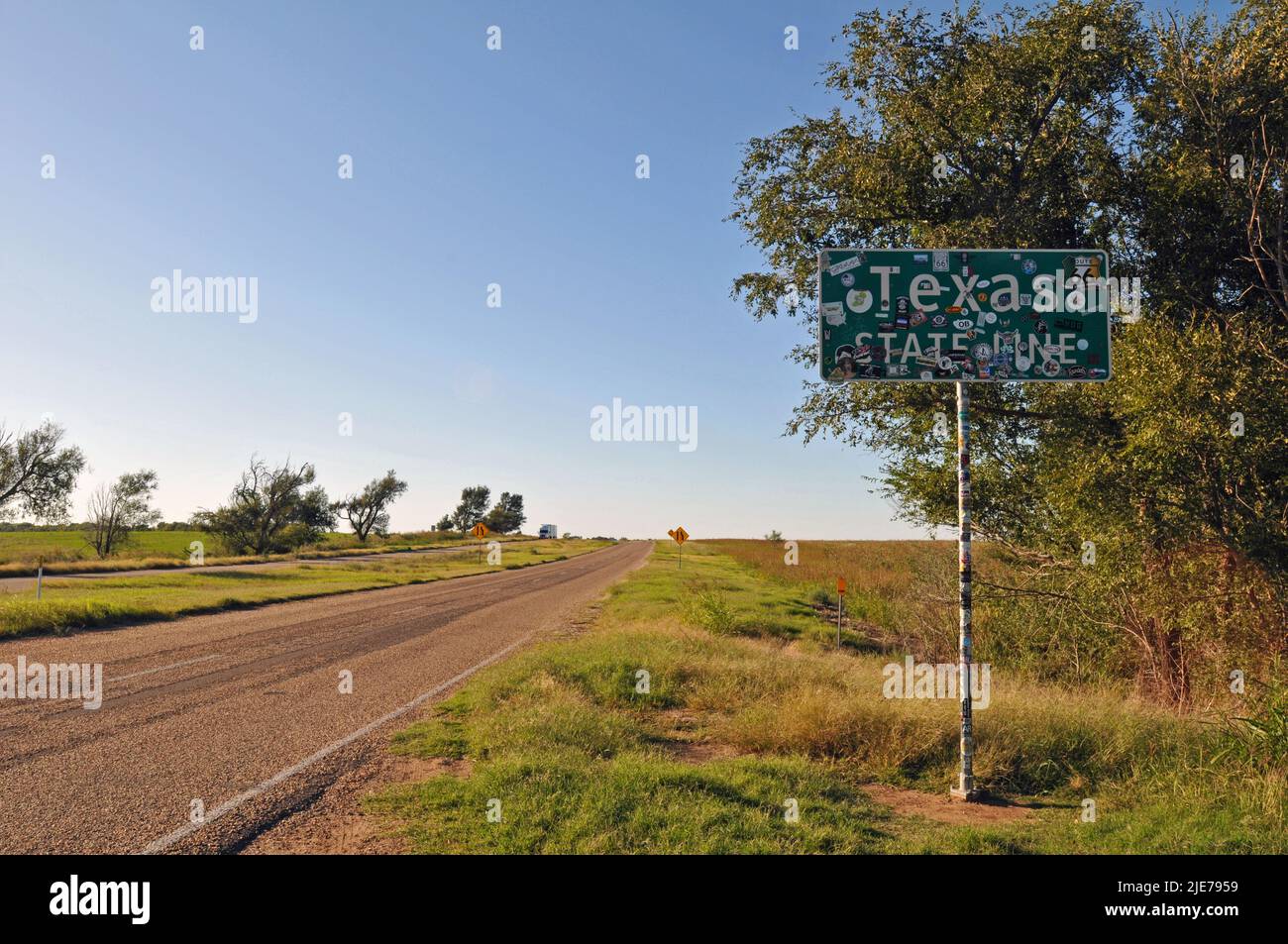 A sign covered in stickers marking the Texas state line stands alongside historic Route 66 outside the small Oklahoma town of Texola. Stock Photo