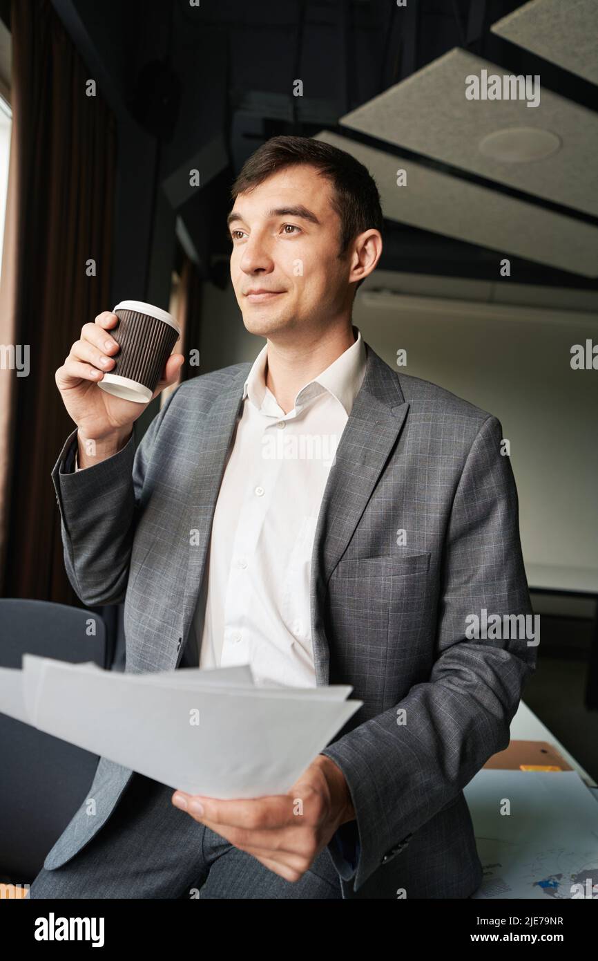 Male drinking coffee at his workplace while keeping papers Stock Photo