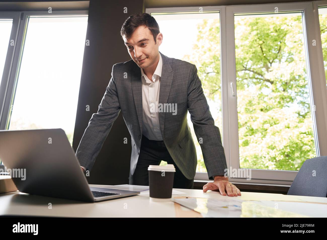 Young clerical worker bending over laptop on table Stock Photo