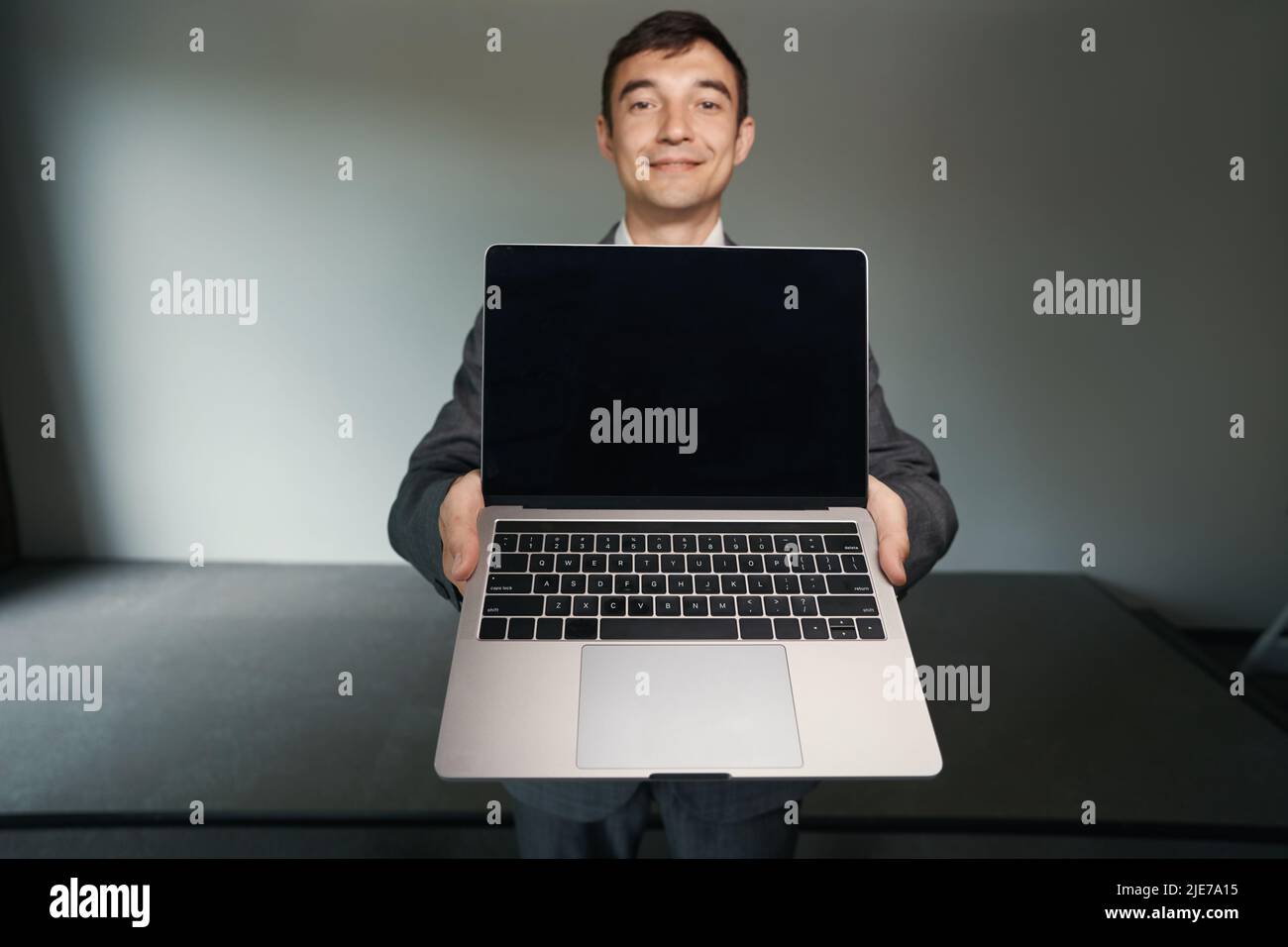 Clerical worker advertising laptop before camera in office Stock Photo