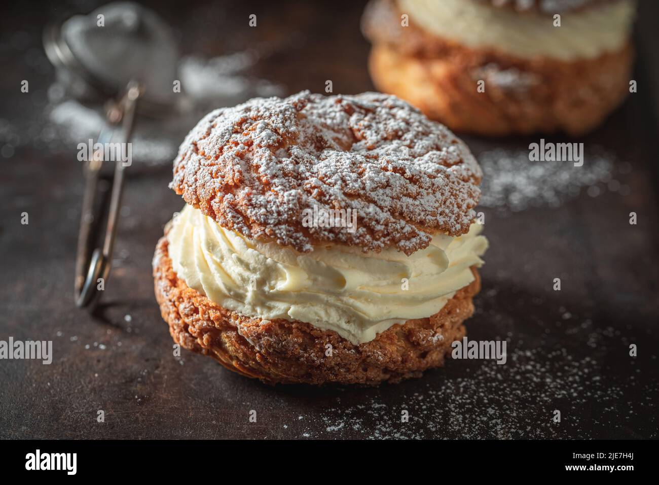 Tasty and homemade cream puffs with powdered sugar in strainer. Cream