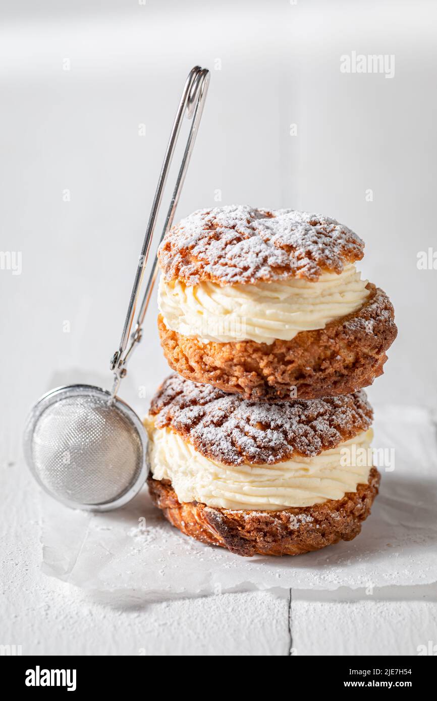 Sweet and yummy cream puffs with powdered sugar in strainer. Cream