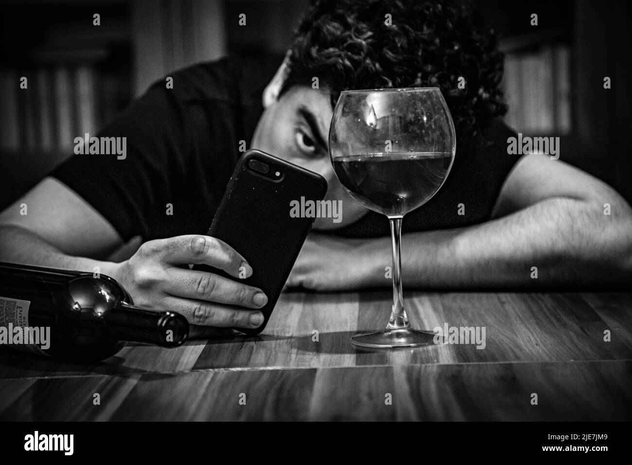 Drinking alone, young man sitting at bar counter with wine, alcoholic, sad, depressed, drunk, alcohol addiction, abuse, alcoholism concept Stock Photo