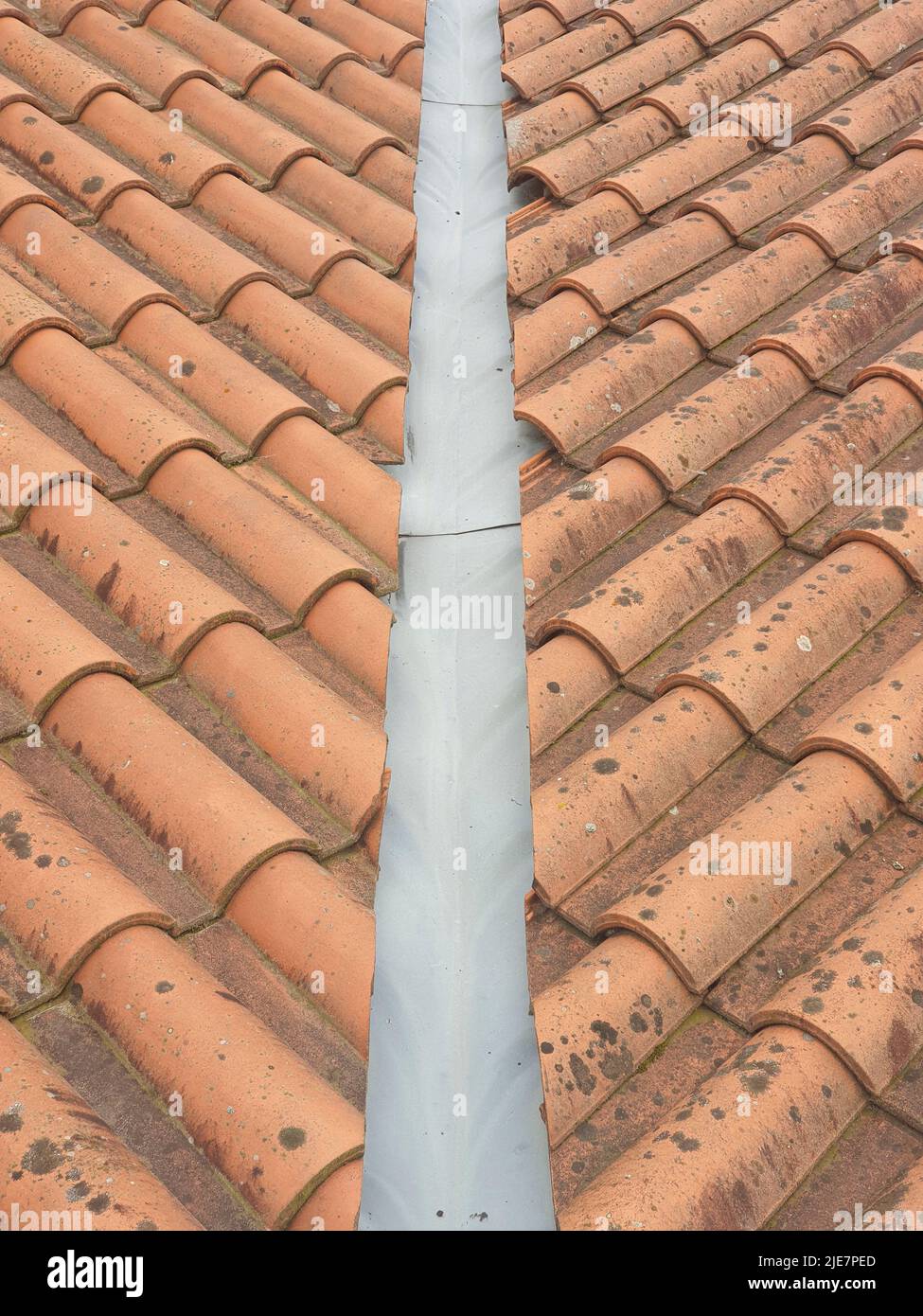 Closeup of red clay roof tiles with downspout in the middle of the roof Stock Photo