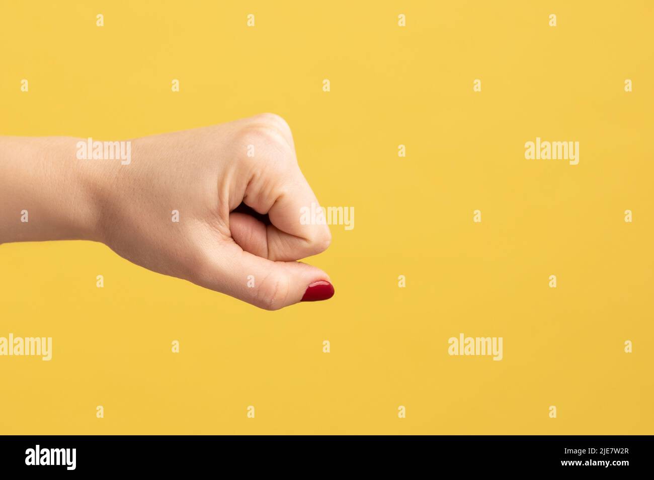 Profile side view closeup of woman hand showing boxing fists with hand, attack or defense against problems. Indoor studio shot isolated on yellow background. Stock Photo