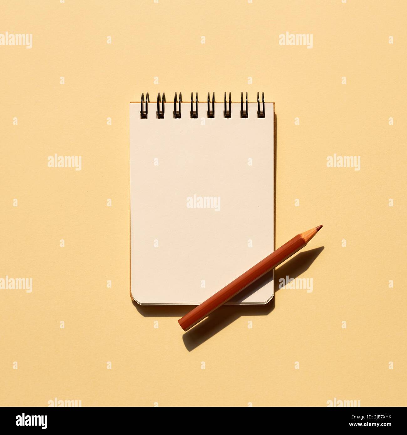 Blank notebook and colored pencil on beige background. top view, copy space Stock Photo