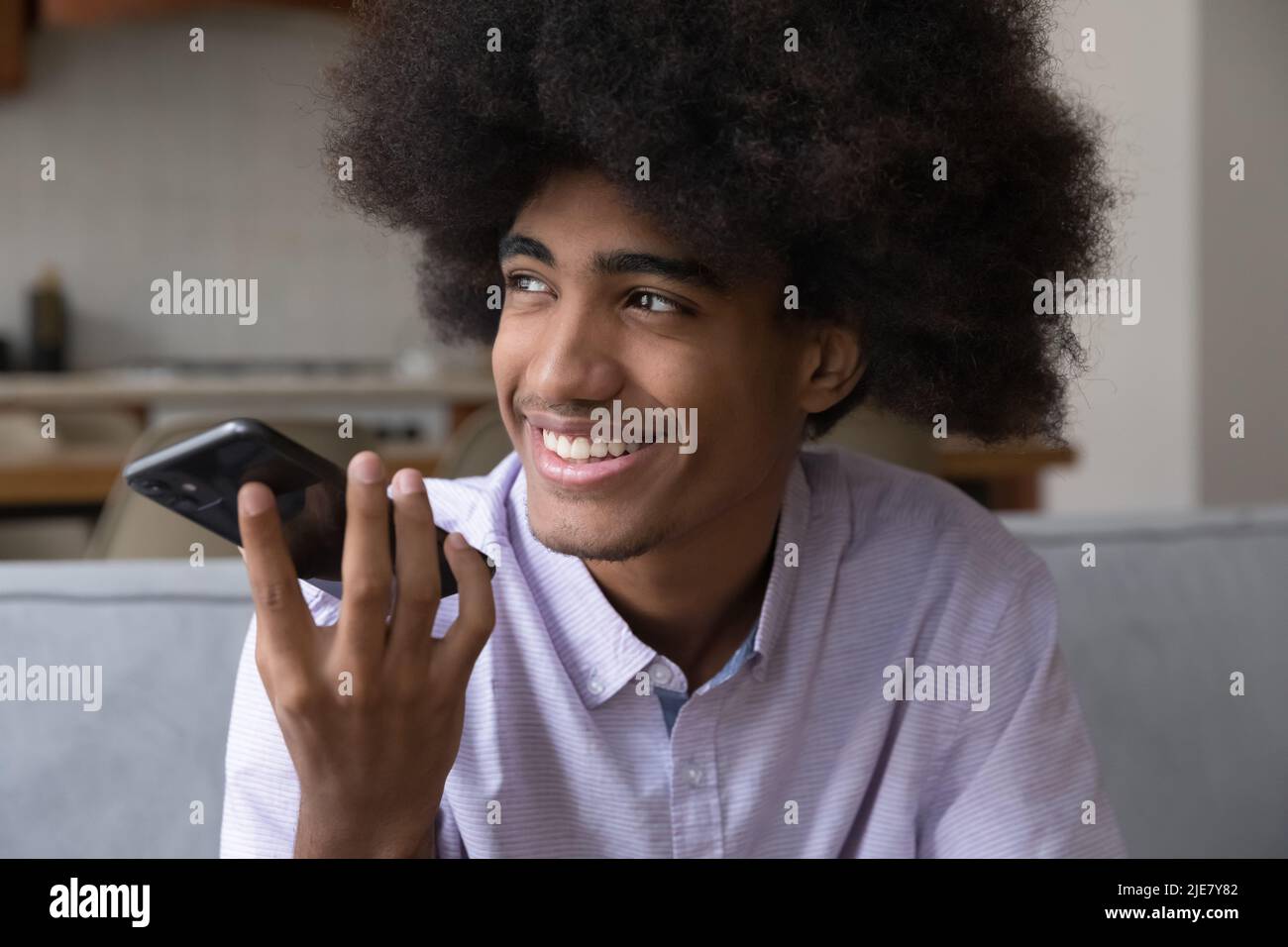 African guy holds smartphone make call speaking on speaker phone Stock Photo
