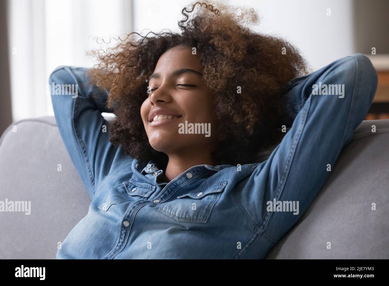 Closeup of African teenage girl closed eyes relaxing on sofa Stock Photo