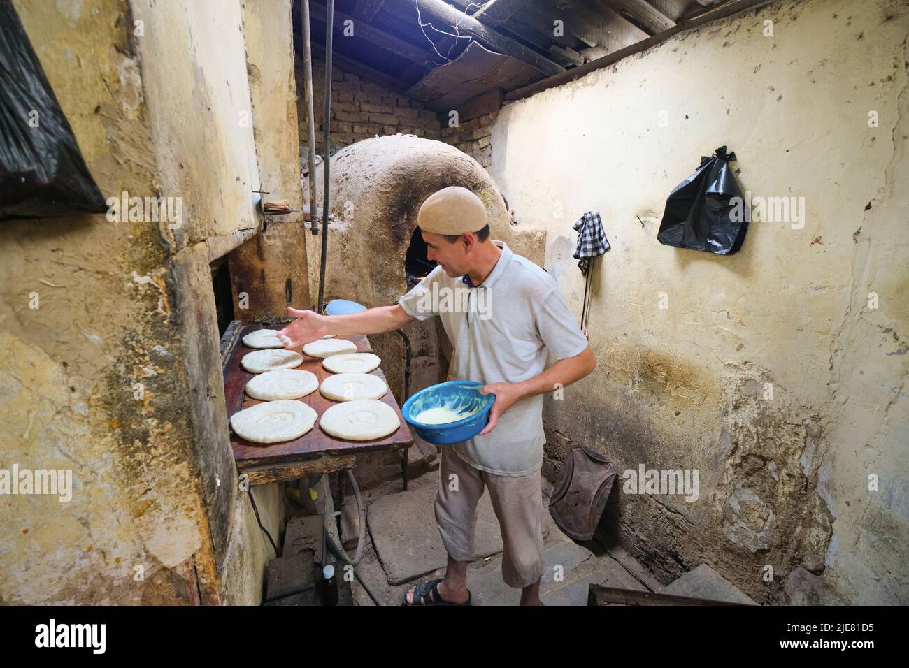 A baker busy prepping non bread dough for tandir oven cooking. This operation is a typical small, local, hidden behind a house, set up. In Namangan, F Stock Photo