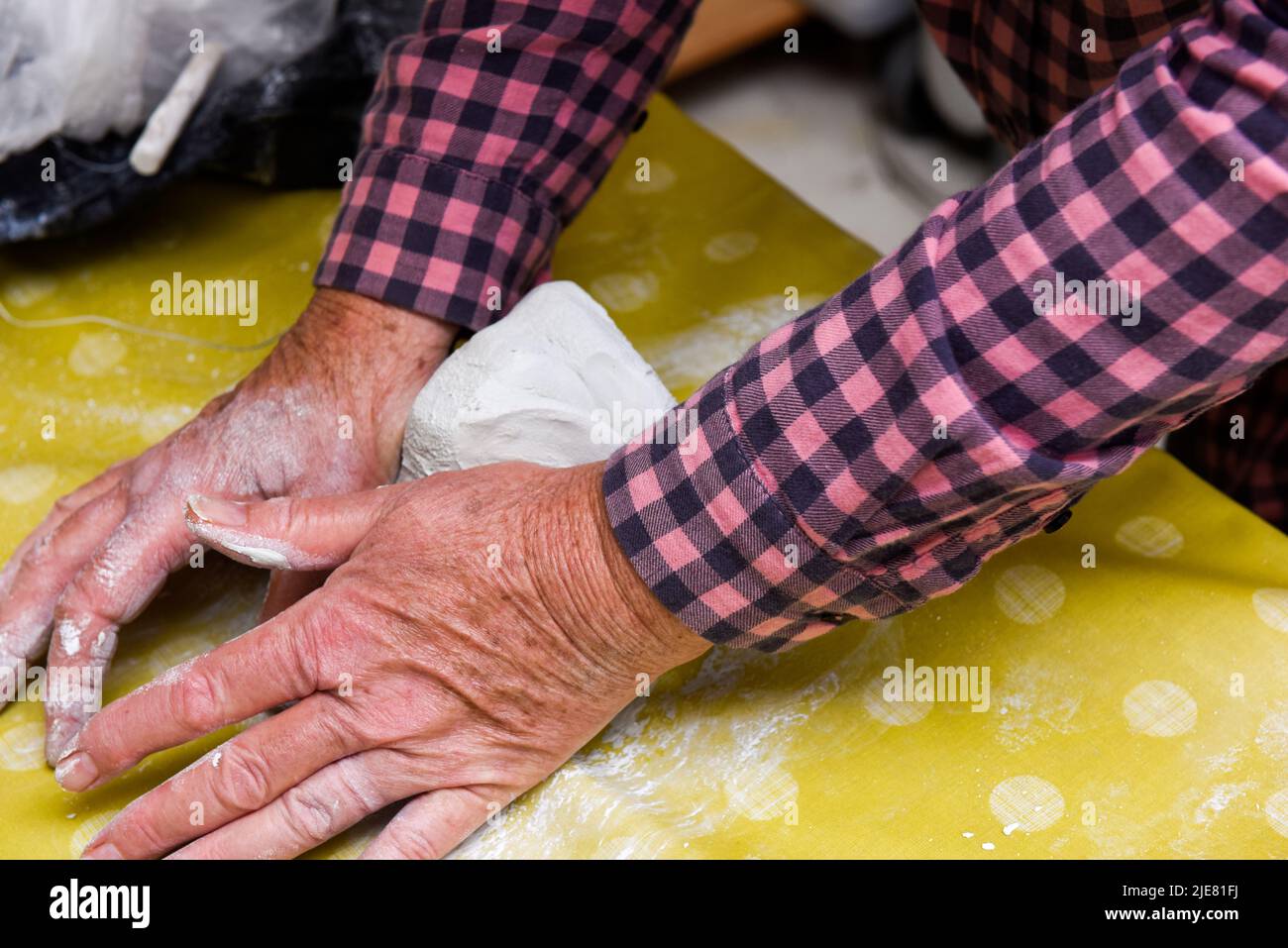 Female hands making ceramic art and pottery in a workshop class for mature people Stock Photo