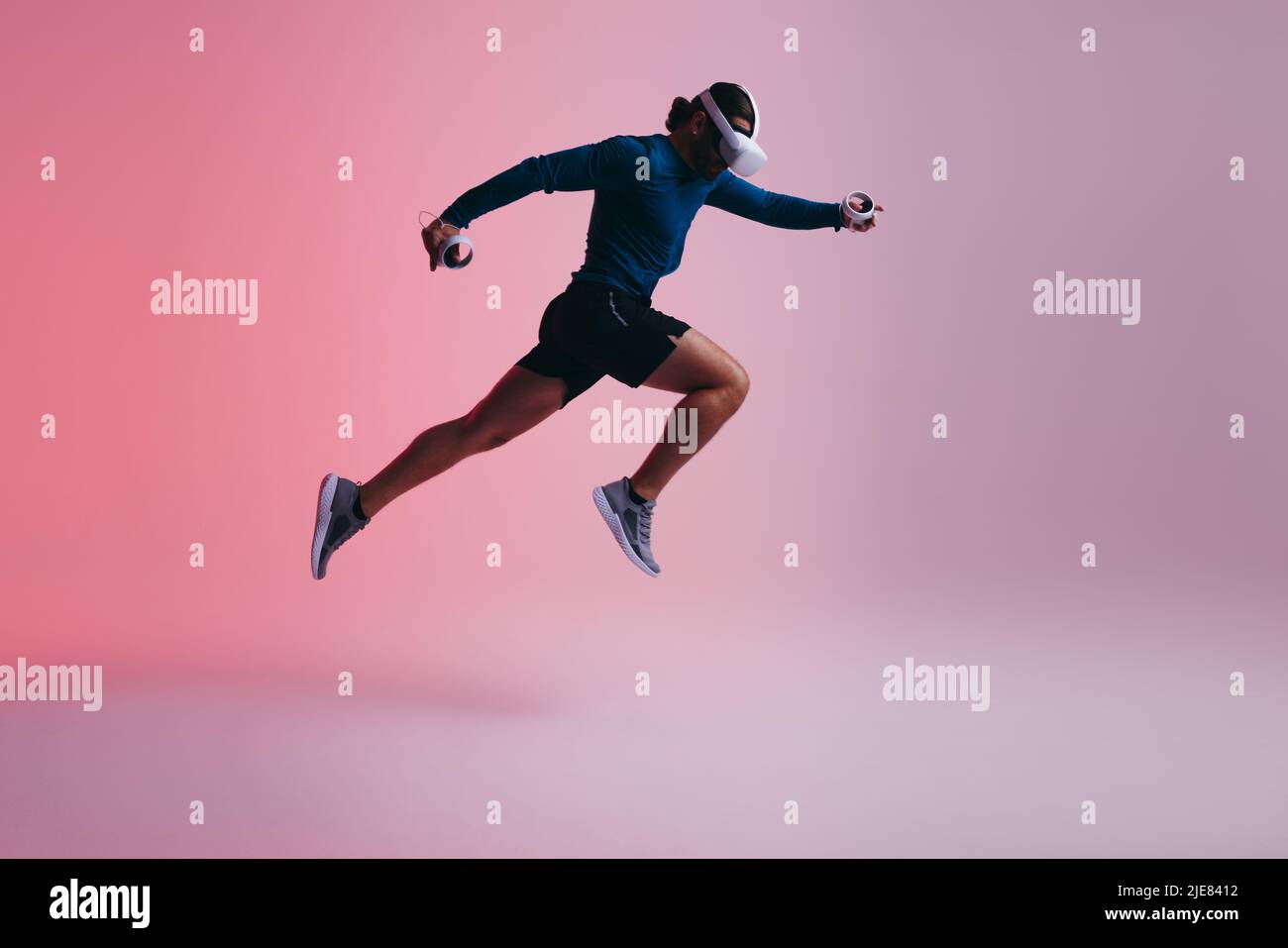 Athletic young man running mid air while wearing virtual reality goggles. Active young man working out in the metaverse. Sporty young man exploring a Stock Photo