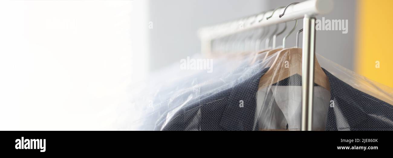 Clothes in plastic bags hanging on hanger in laundry closeup Stock