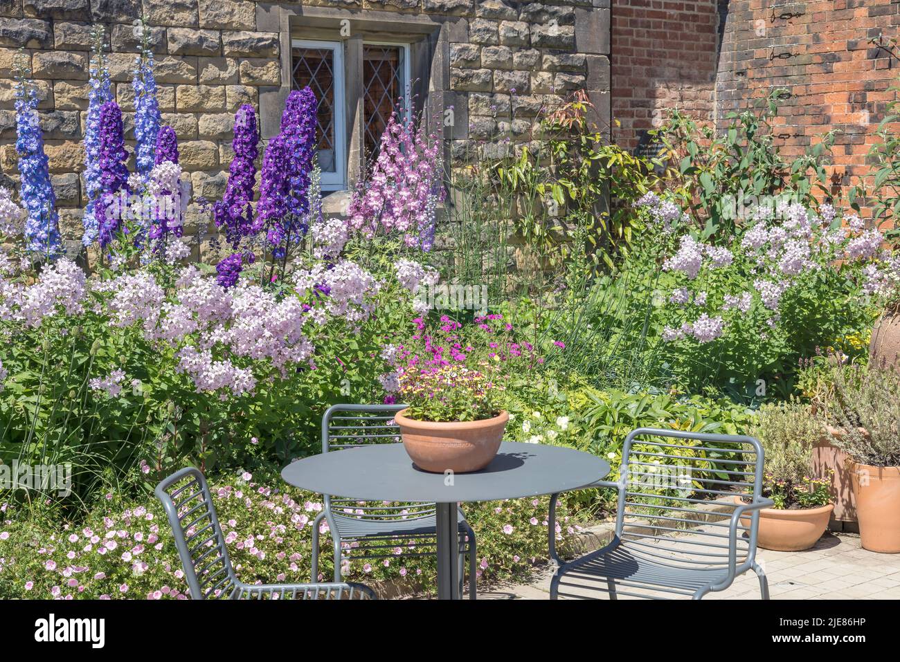 Small cottage garden with terracotta planters, table and chairs. Stock Photo