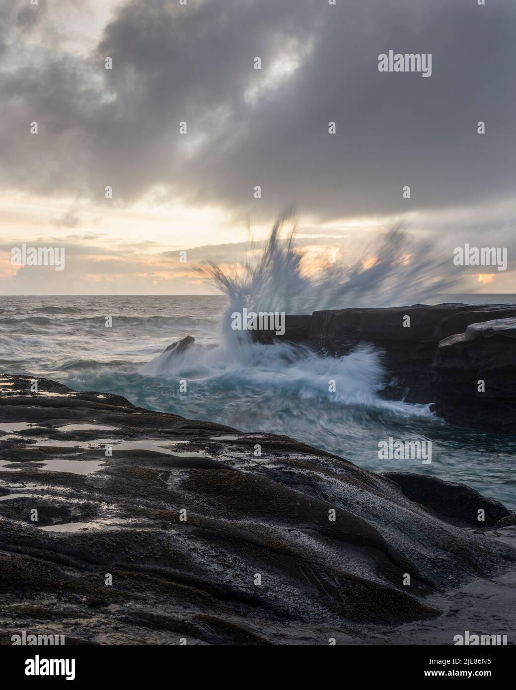 Ocean waves crashing on rocks at Muriwai beach, Auckland. Vertical format. Stock Photo