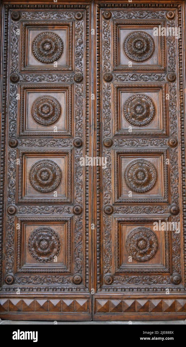 Ancient solid wood doors with hand-carved decorations by local artists, in the splendid historic center of Lucca Stock Photo