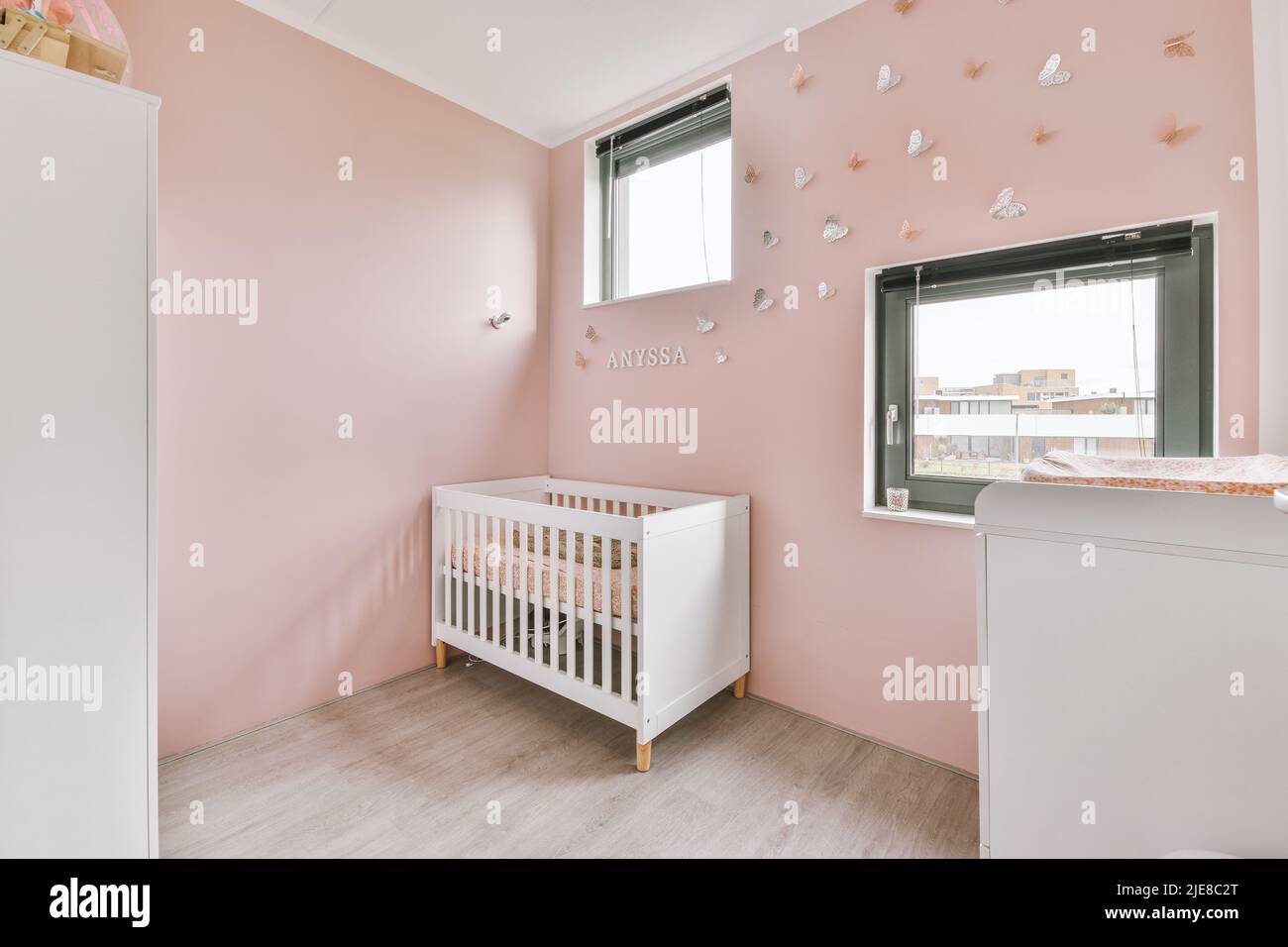Interior of white room with baby crib and armchair near window with