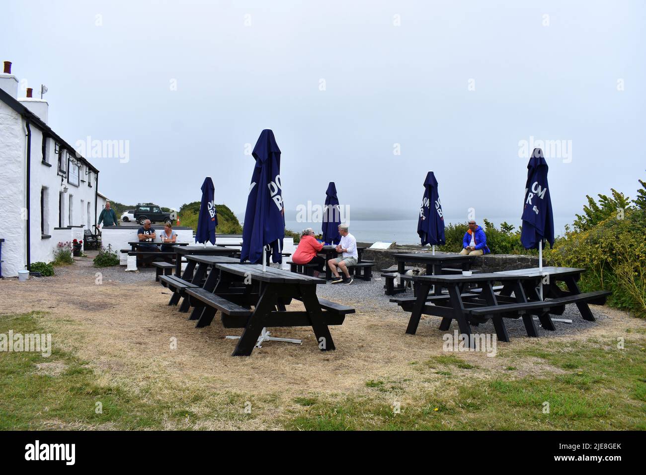 People sitting having a drink outside The Old Point House, Angle, Pembrokeshire, Wales Stock Photo