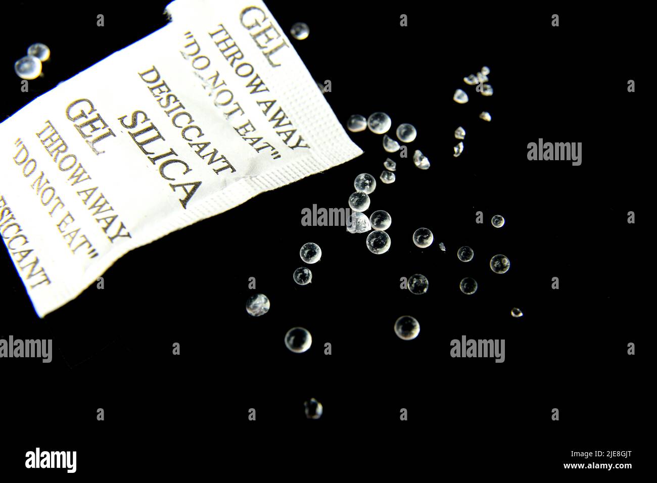 Open packet of Silica Gel Beads on black background. Macro photography