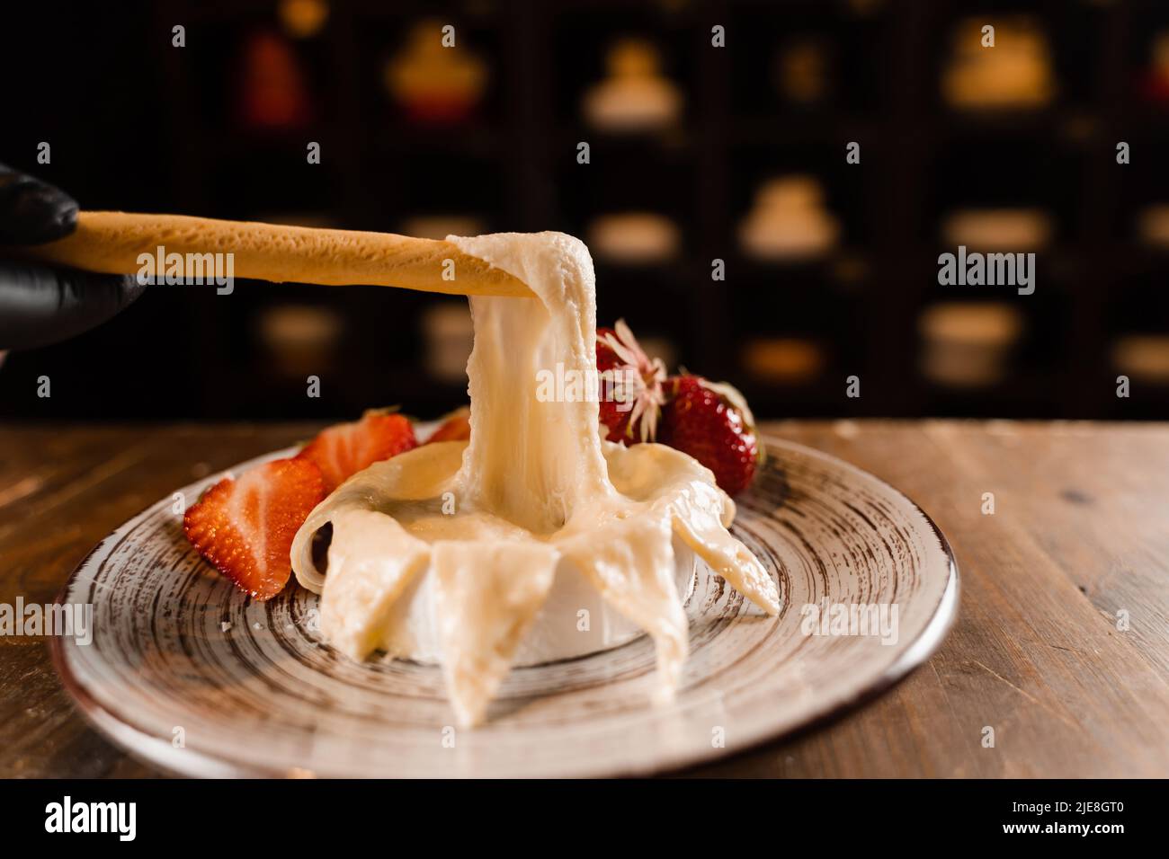 Eating hot baked camembert cheese with grissini sticks. Stretching