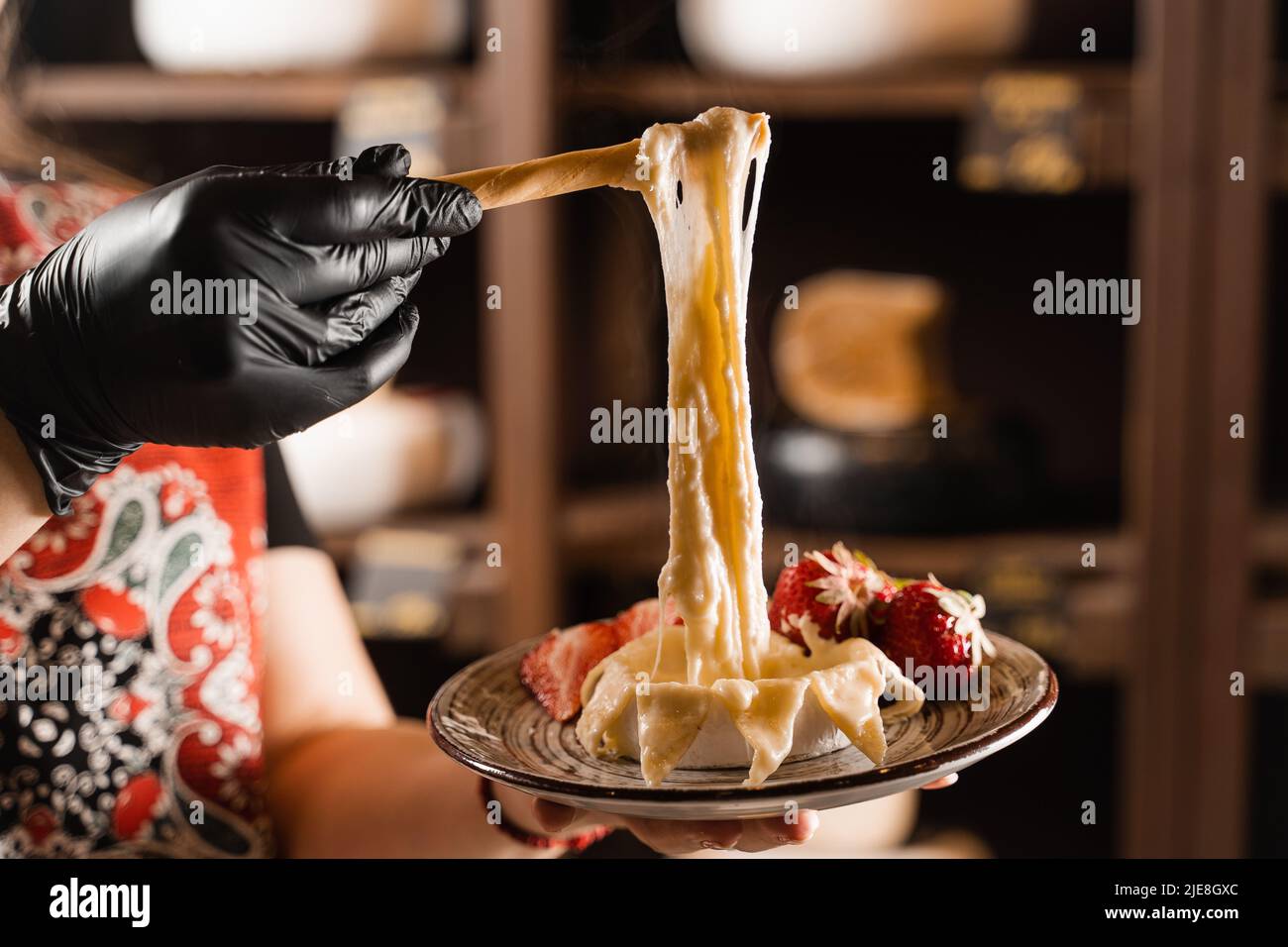 Eating hot baked camembert cheese with grissini sticks. Stretching