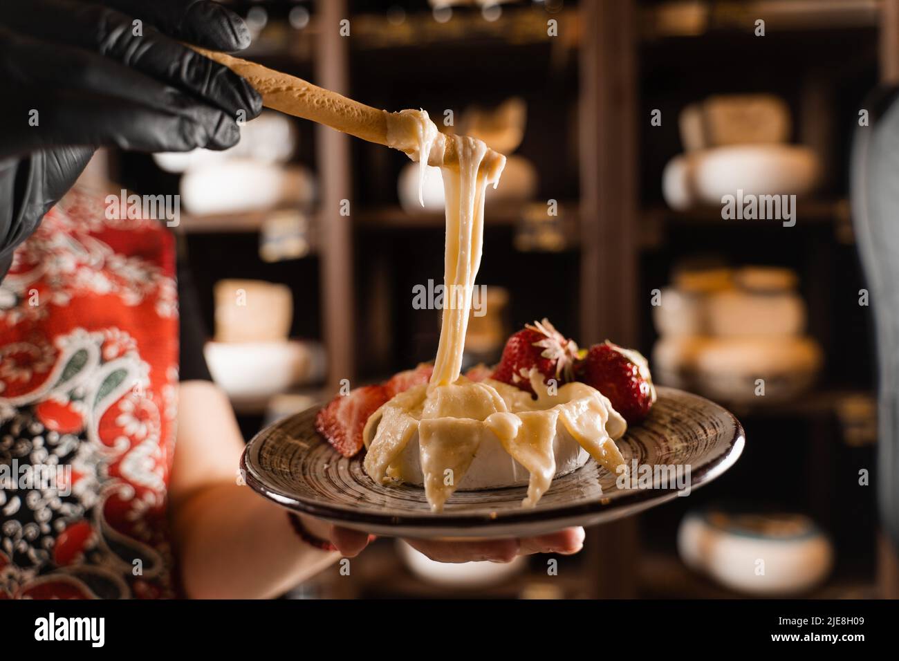 Eating hot baked camembert cheese with grissini sticks. Stretching