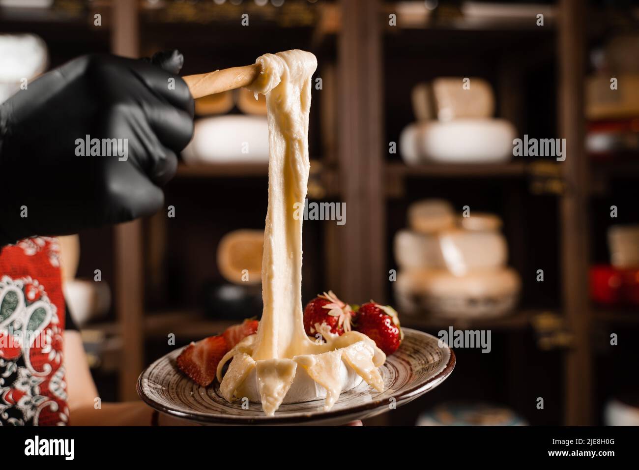 Eating hot baked camembert cheese with grissini sticks. Stretching