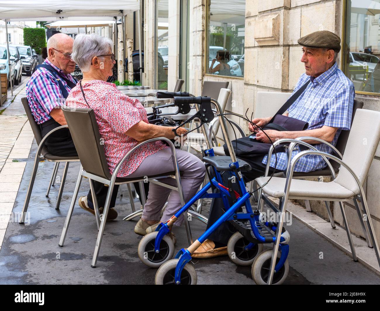 Three elderly people sitting on bar terrace awaiting service - Tours, France. Stock Photo