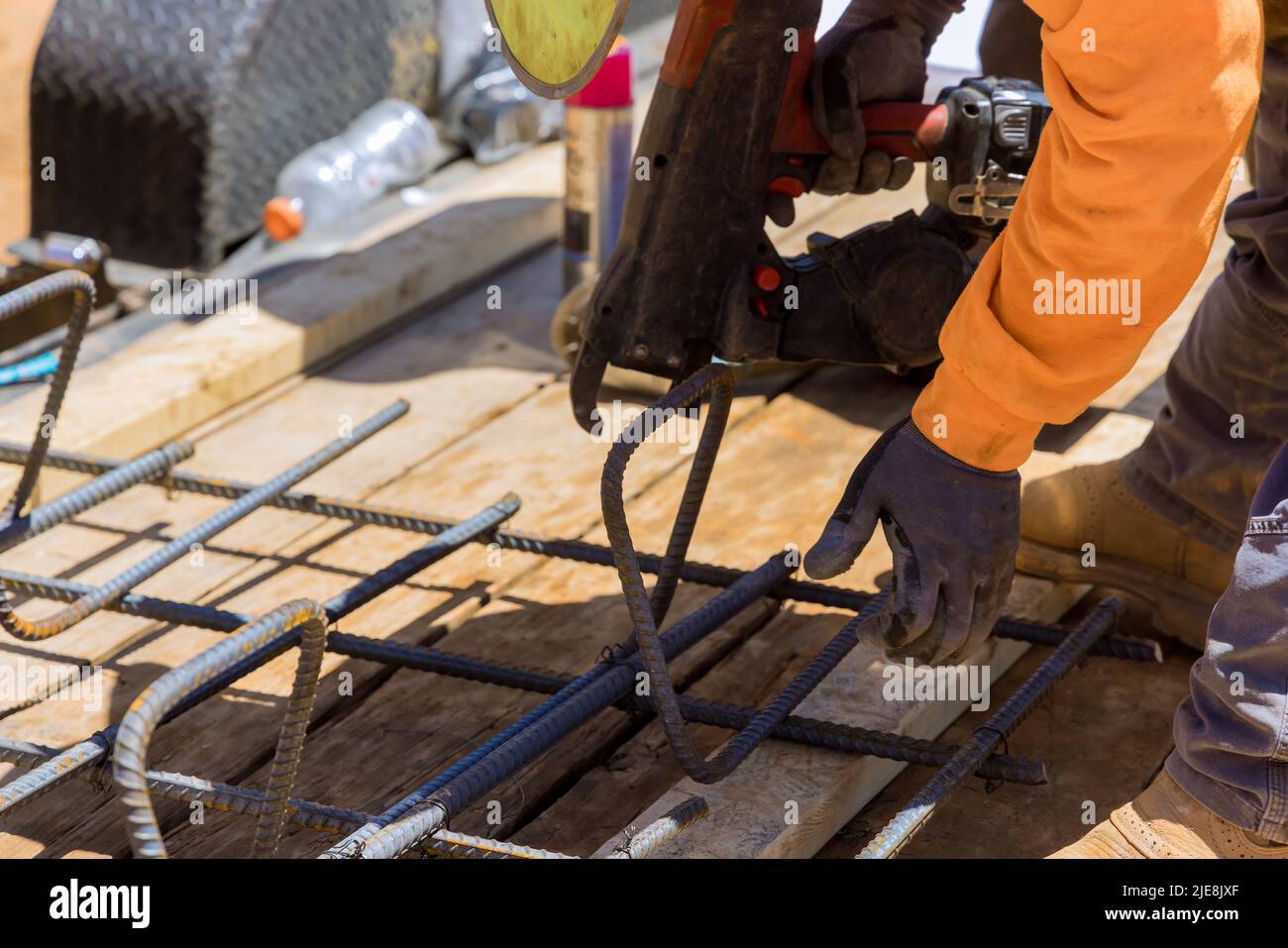 Using a rebar tying tool, construction worker twists steel bars with wire rods Stock Photo