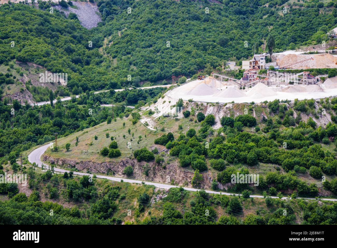 A natural stepped quarry rich in minerals is located near winding intermountain road, against backdrop of Rhodope Mountains and hills with extensive e Stock Photo