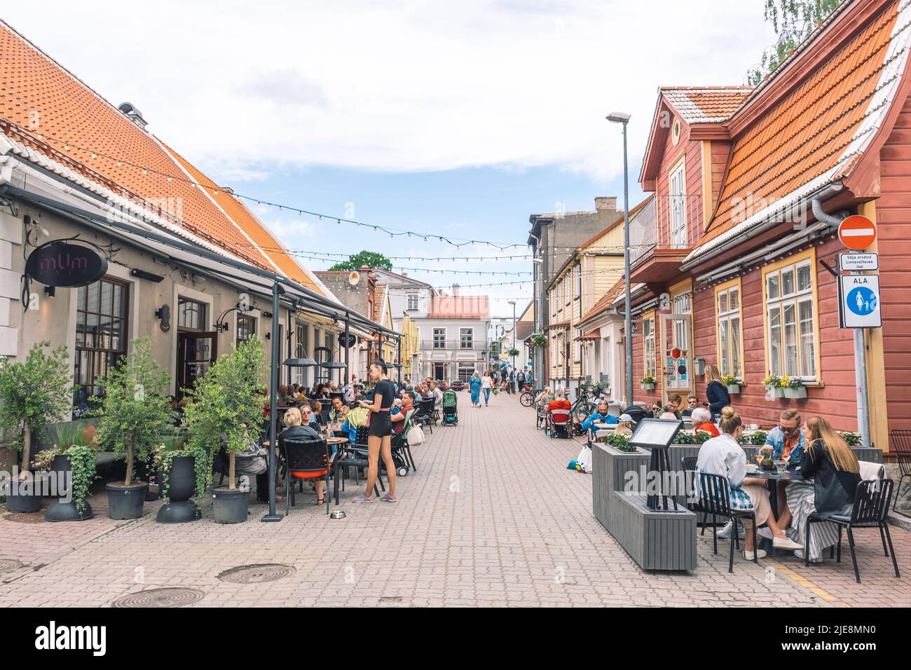 Parnu old town street with traditional houses and people sitting at the tables of cafes and restaurants Stock Photo