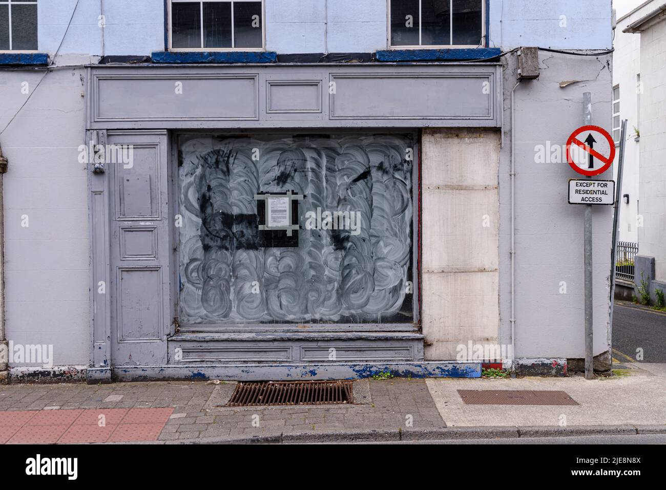 Shop with a boarded up door and whitewashed window after going out of business.  Republic of Ireland. Stock Photo
