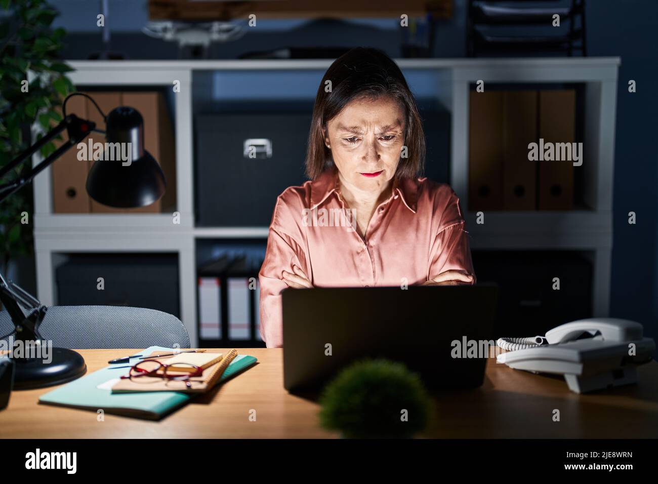 Middle age hispanic woman working using computer laptop late at night ...