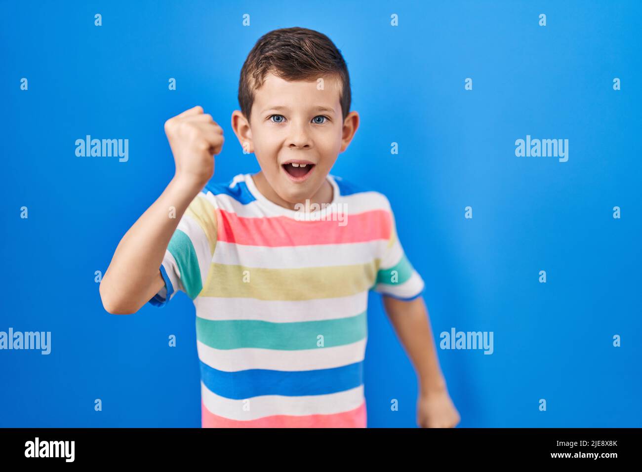 Young caucasian kid standing over blue background angry and mad raising ...